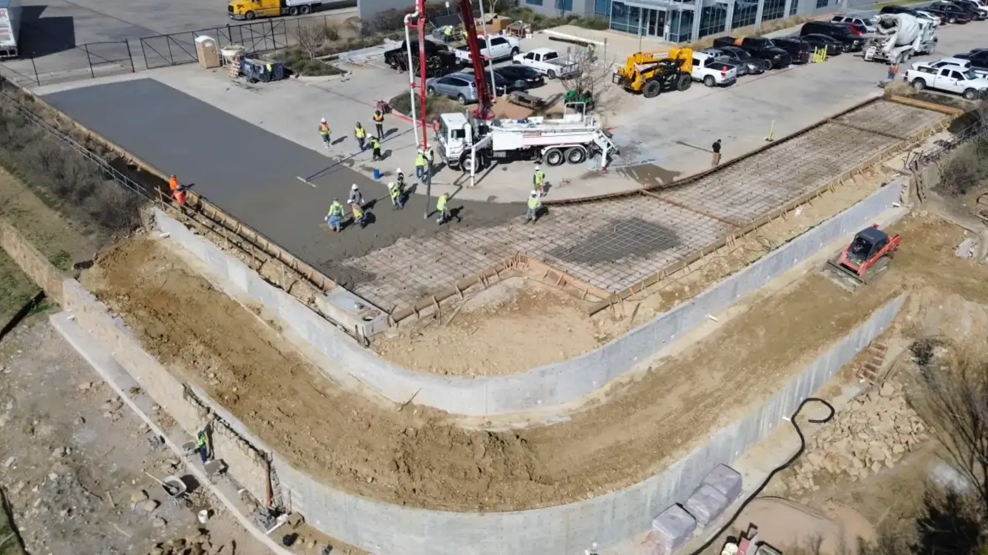Aerial view of a construction site with workers pouring concrete.